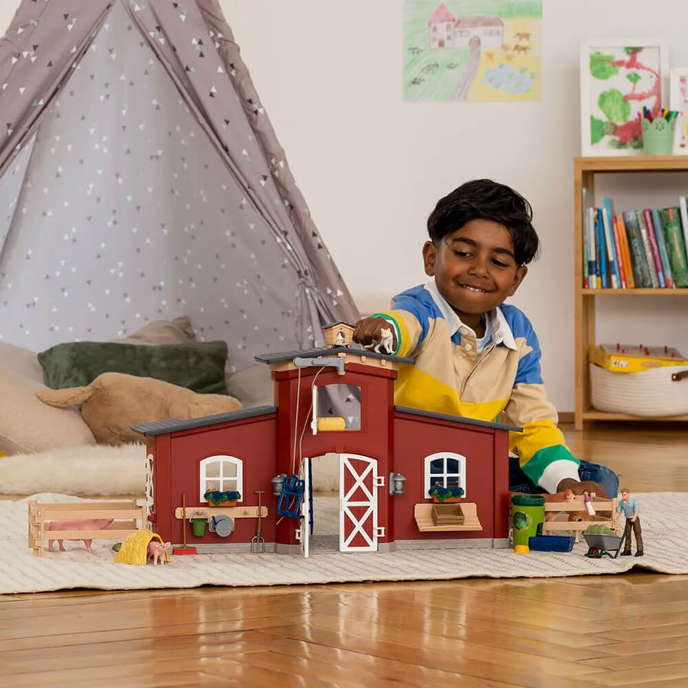 Boy playing with the Schleich Farm World Large Barn with Animals and Accessories Set