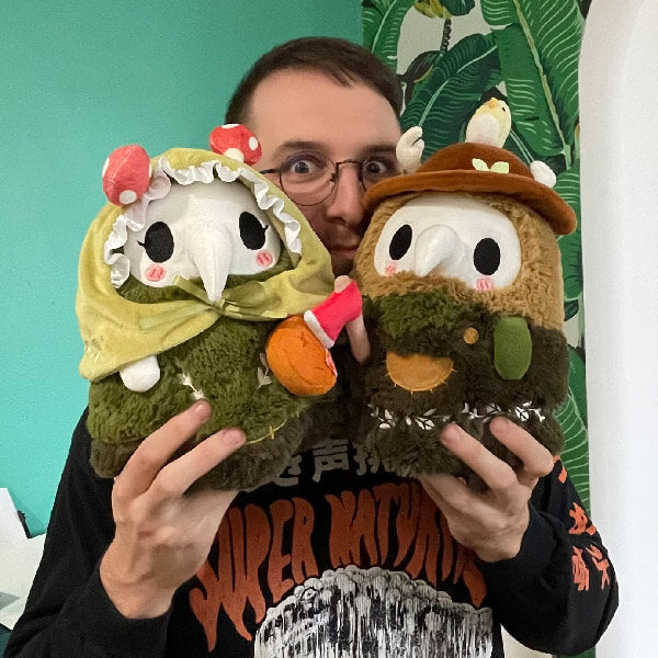 Man holding the Squishable Mini Woodland Plague Doctor & Nurse Plush Set